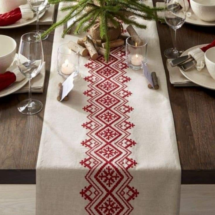 Cream table runner with a central red geometric diamond band and tasselled ends.