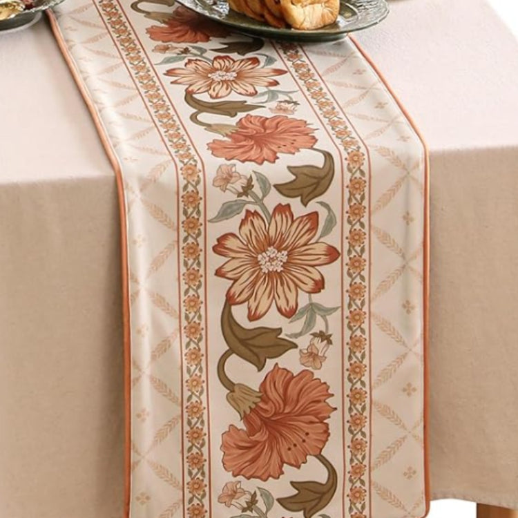 Cream table runner with large rust and beige flowers inside patterned borders.