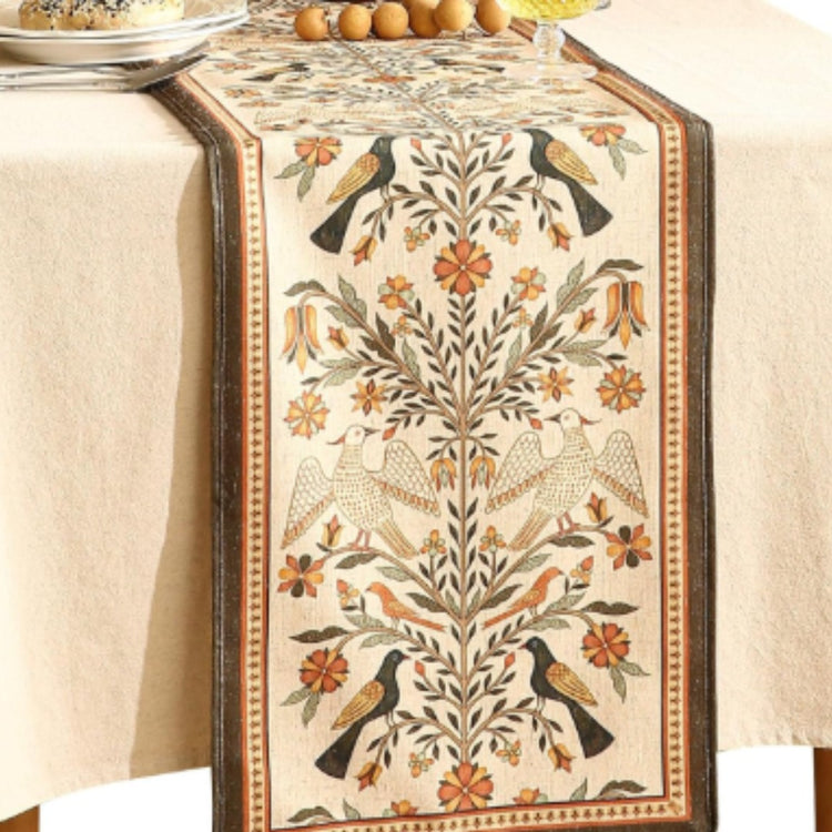 Cream table runner with symmetrical gold and grey botanical motifs and brown borders.