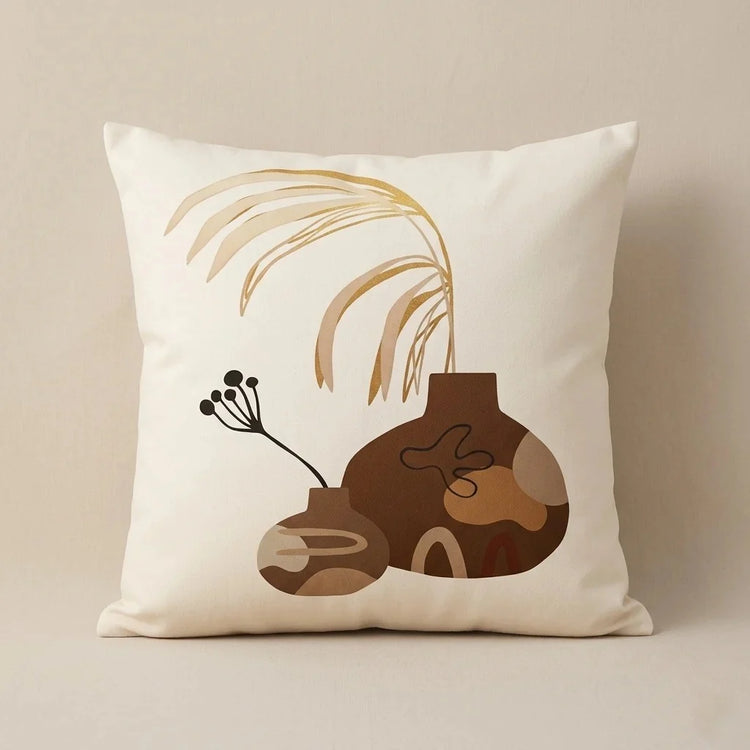 Cream cushion cover with brown abstract forms, a fine black sprig and pale curved lines.