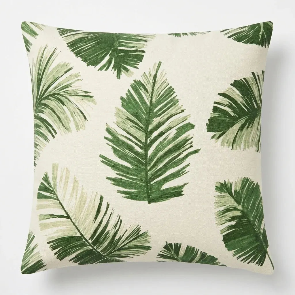 Cream cushion cover with scattered dark green palm and tropical leaves.
