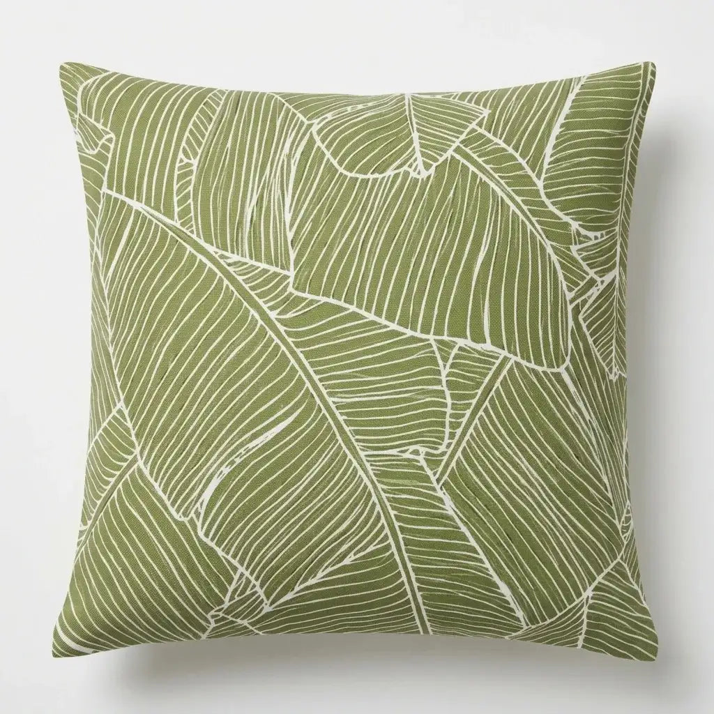 Olive green cushion cover with large pale outlined tropical leaves.