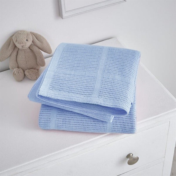Folded pale blue cellular blanket on a white cabinet beside a plush rabbit.