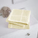 Folded pale yellow cellular blanket on a white cabinet beside a plush rabbit.