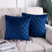 Two navy cushion covers with diamond stitching on a sofa.