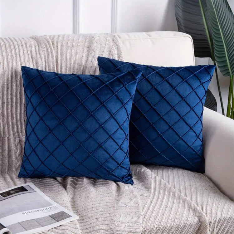 Two navy cushion covers with diamond stitching on a sofa.
