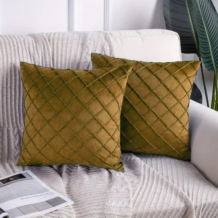 Two ochre cushion covers with diamond stitching on a sofa.