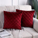 Two burgundy cushion covers with diamond stitching on a sofa.