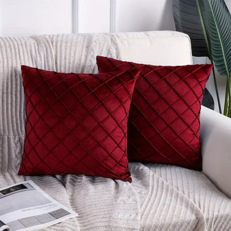 Two burgundy cushion covers with diamond stitching on a sofa.