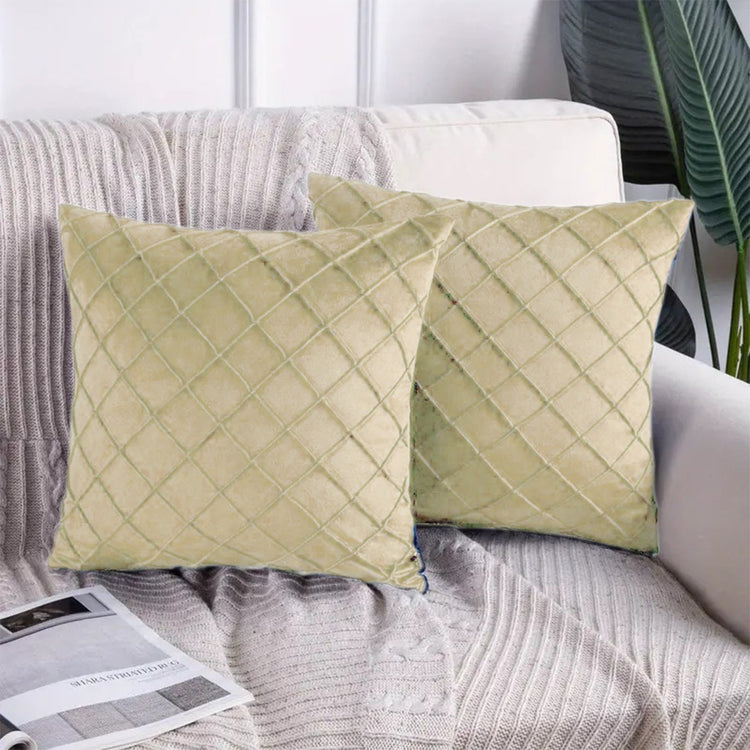 Two cream cushion covers with diamond stitching on a sofa.