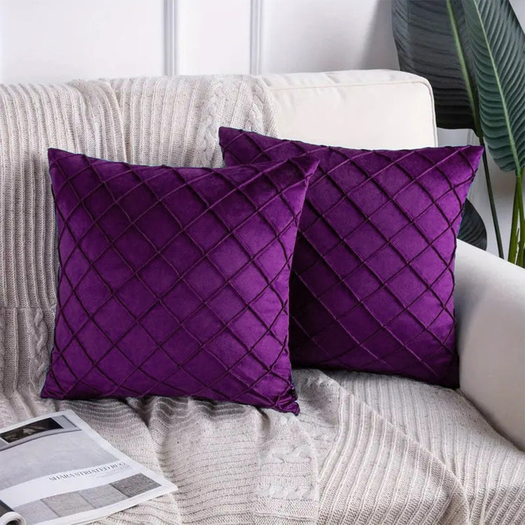 Two purple cushion covers with diamond stitching on a sofa.