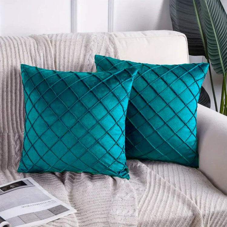 Two teal cushion covers with diamond stitching on a sofa.