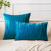 Teal square and rectangular cushion covers with angular stitched lines on a bed.