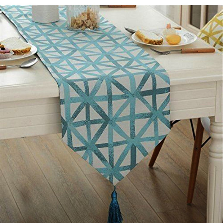Teal and white geometric table runner with a pointed tasselled end.