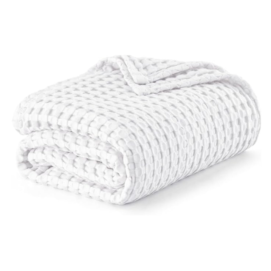 Folded white waffle-weave blanket on a white background.