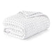 Folded white waffle-weave blanket on a white background.
