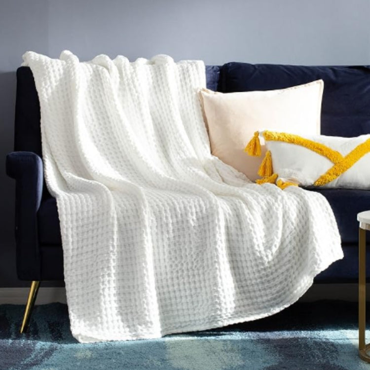 White waffle-weave blanket draped over a dark sofa.