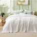 White waffle-weave blanket spread across a bed in a bright bedroom.