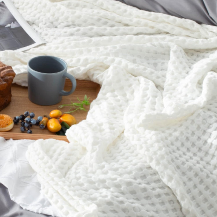 Close-up of white waffle-weave blanket fabric beside a breakfast tray.