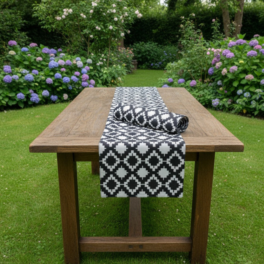 Black and white diamond-pattern table runner on an outdoor wooden table.