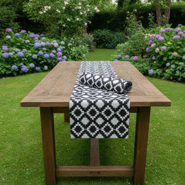 Black and white diamond-pattern table runner on an outdoor wooden table.