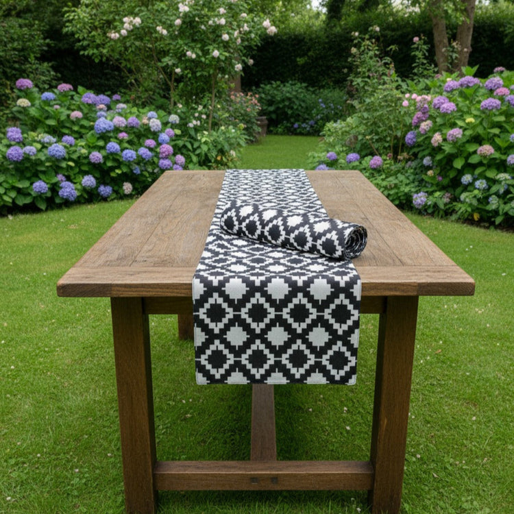 Black and white diamond-pattern table runner on an outdoor wooden table.