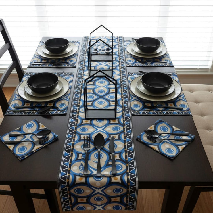 Blue and cream ornamental table runner with matching placemats on a dining table.