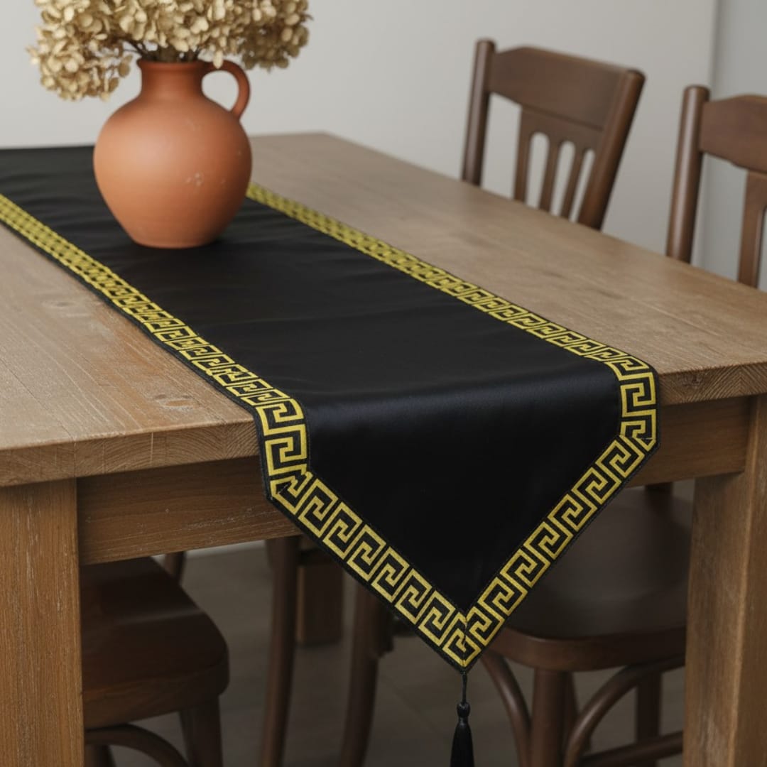Black velvet table runner with a gold geometric border and pointed ends.