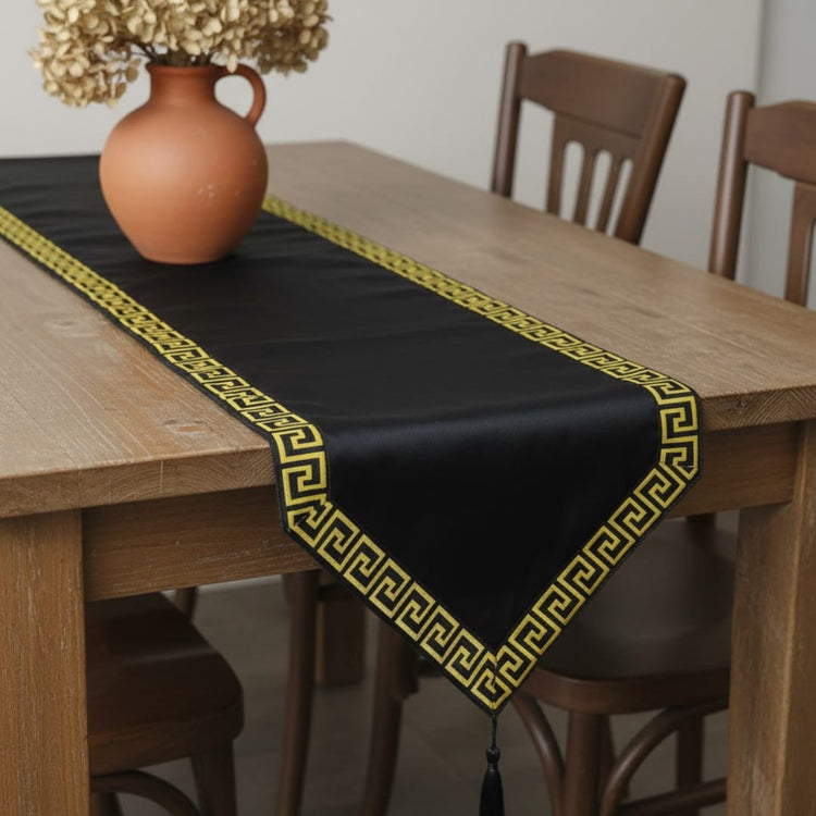 Black velvet table runner with a gold geometric border and pointed ends.