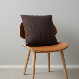Brown cushion cover with a stitched grid pattern displayed on a chair.
