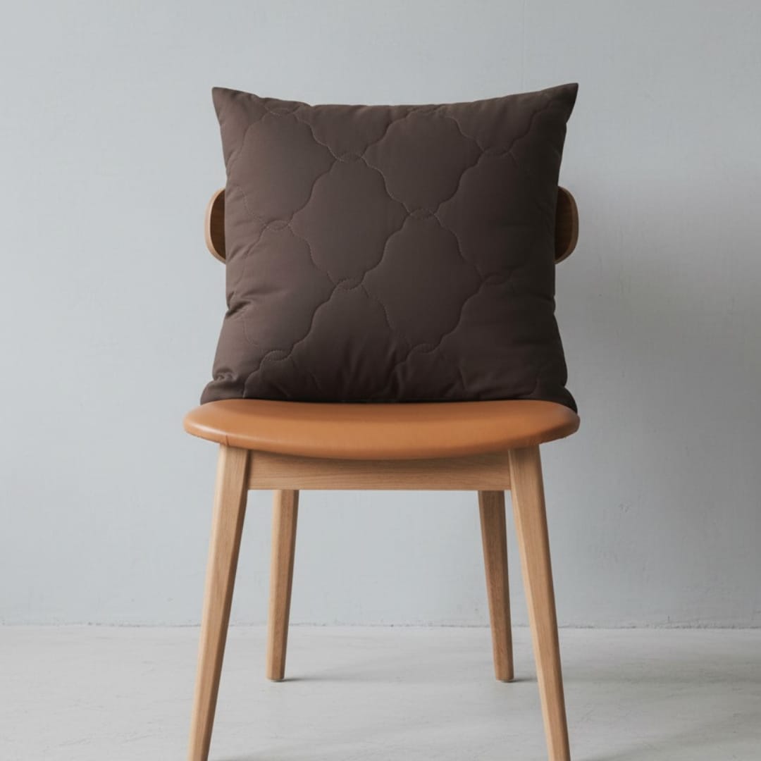 Brown cushion cover with subtle quilted lines displayed on a chair.