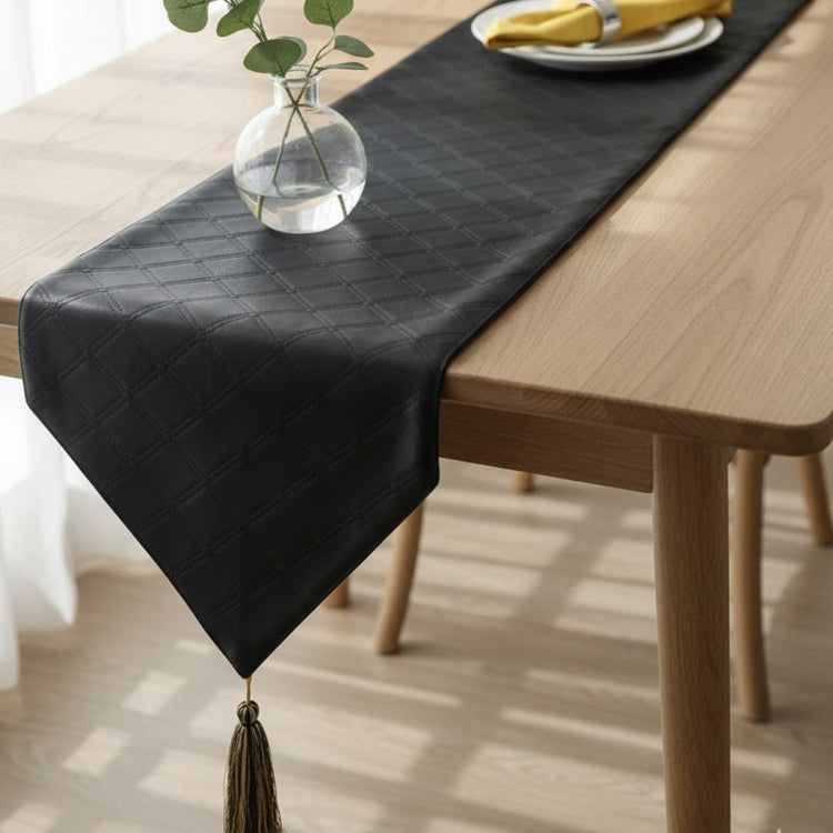 Black textured table runner with a pointed end beneath a glass vase.