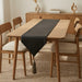 Plain dark table runner on a light wooden dining table.