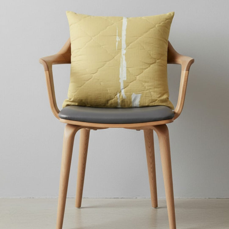 Mustard cushion cover with a pale vertical stitched stripe displayed on a chair.