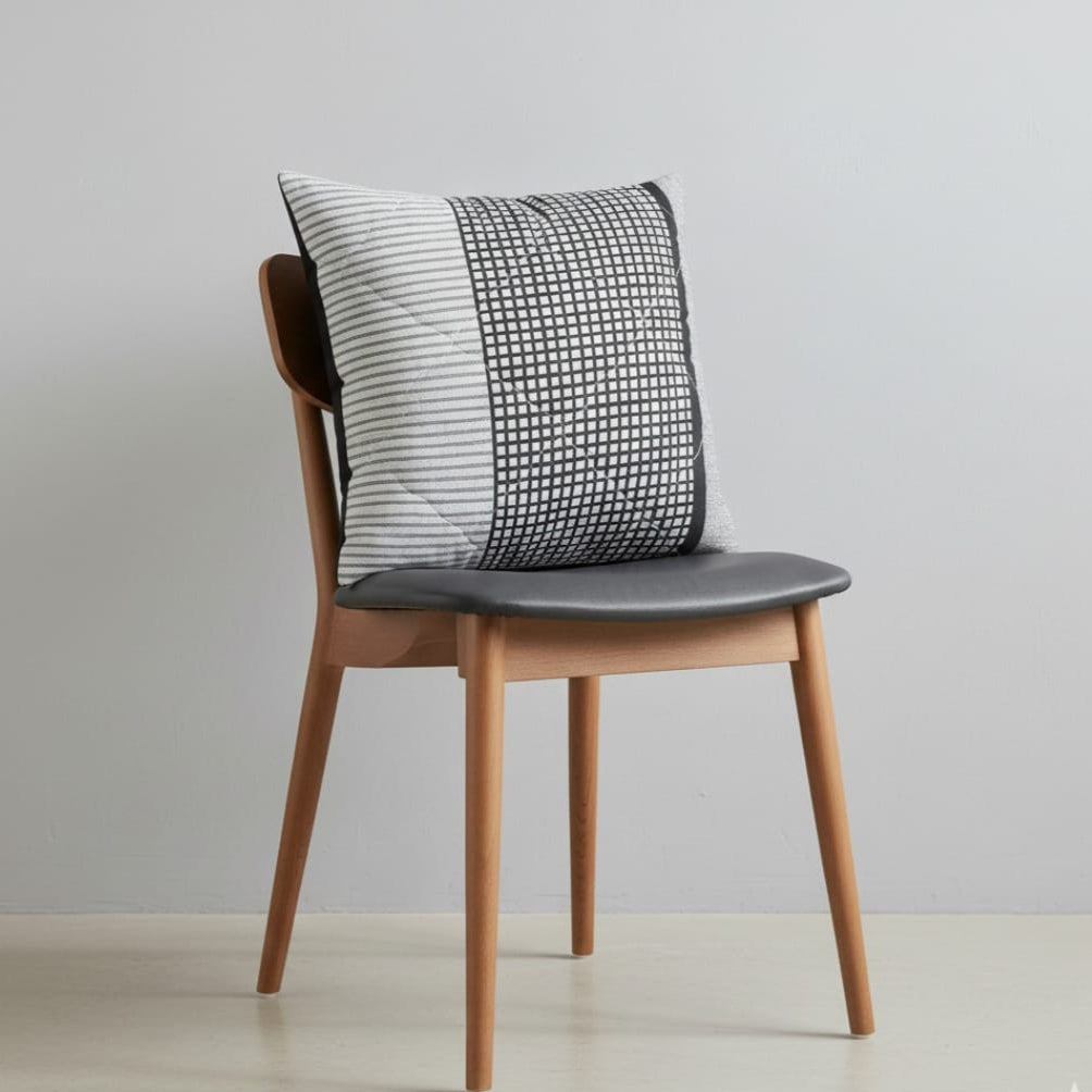 Grey cushion cover with a fine textured pattern displayed on a chair.