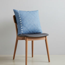 Blue cushion cover with subtle stitched texture displayed on a chair.