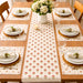 Cream table runner with small repeating red floral motifs and matching placemats.