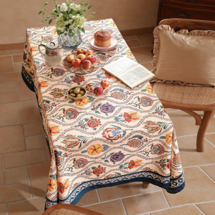 Cream tablecloth with colourful ornamental floral motifs and a dark patterned border.