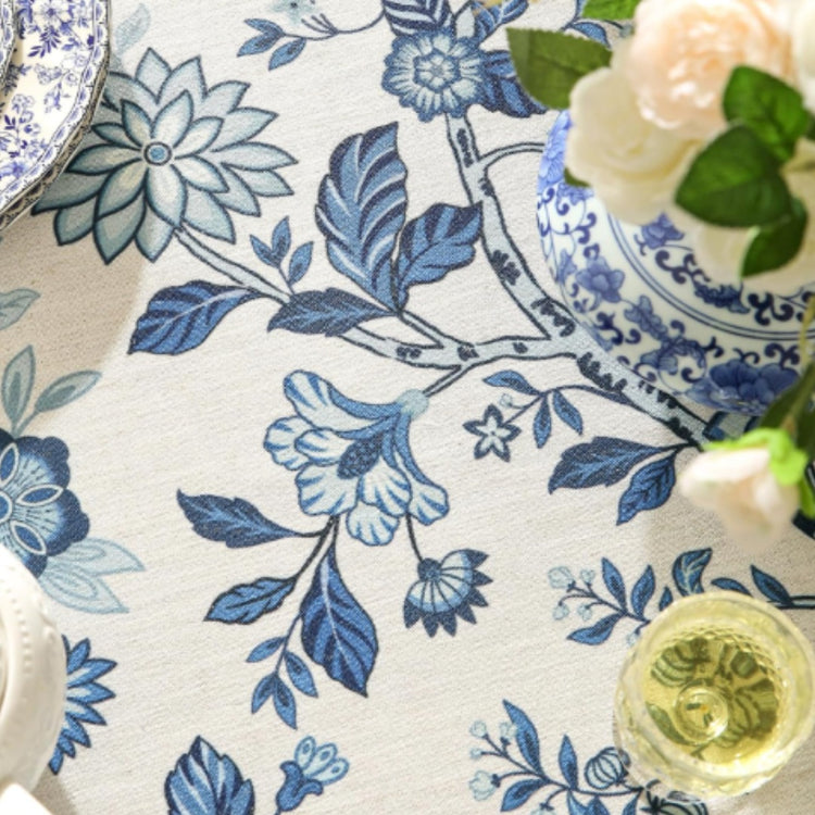 Close-up of blue floral motifs on a cream tablecloth.