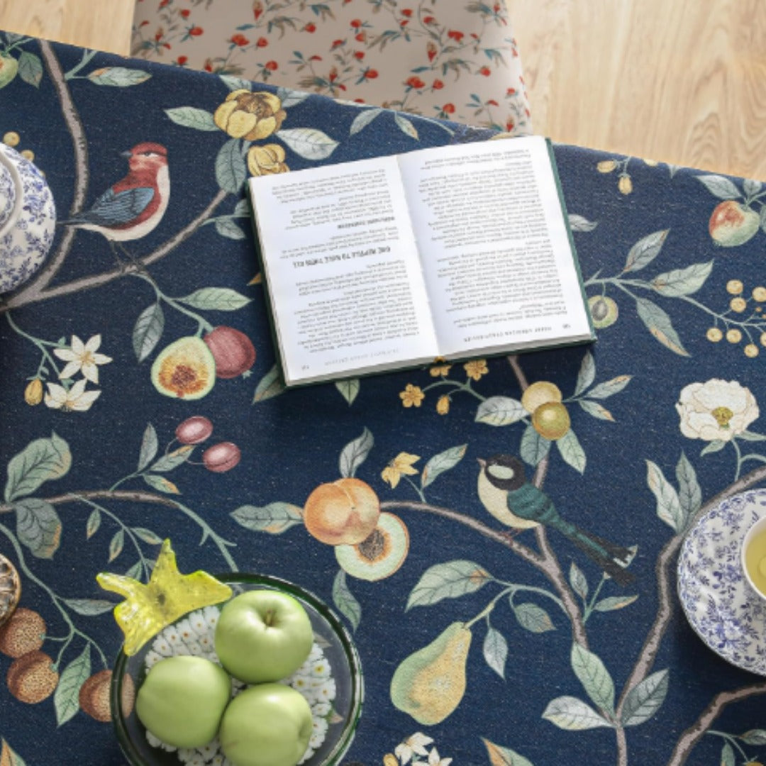 Close-up of botanical vines and fruit motifs on a navy tablecloth.