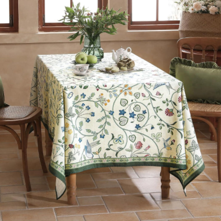 Cream tablecloth with delicate green and blue botanical vines and a green border.
