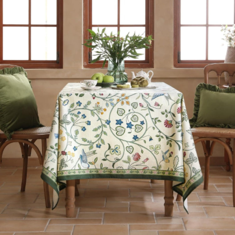 Cream tablecloth with delicate green and blue botanical vines and a green border.