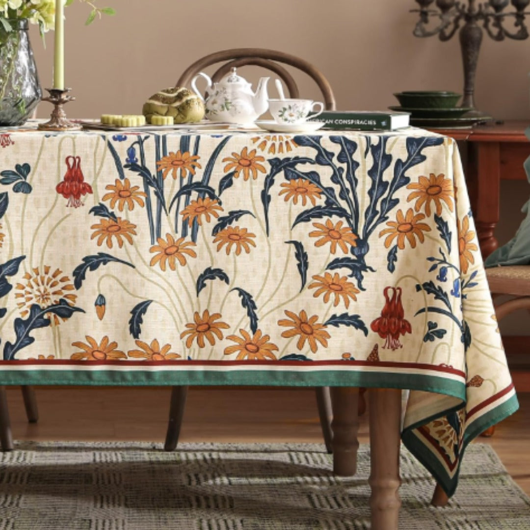 Cream tablecloth with orange and navy botanical motifs and contrasting borders.