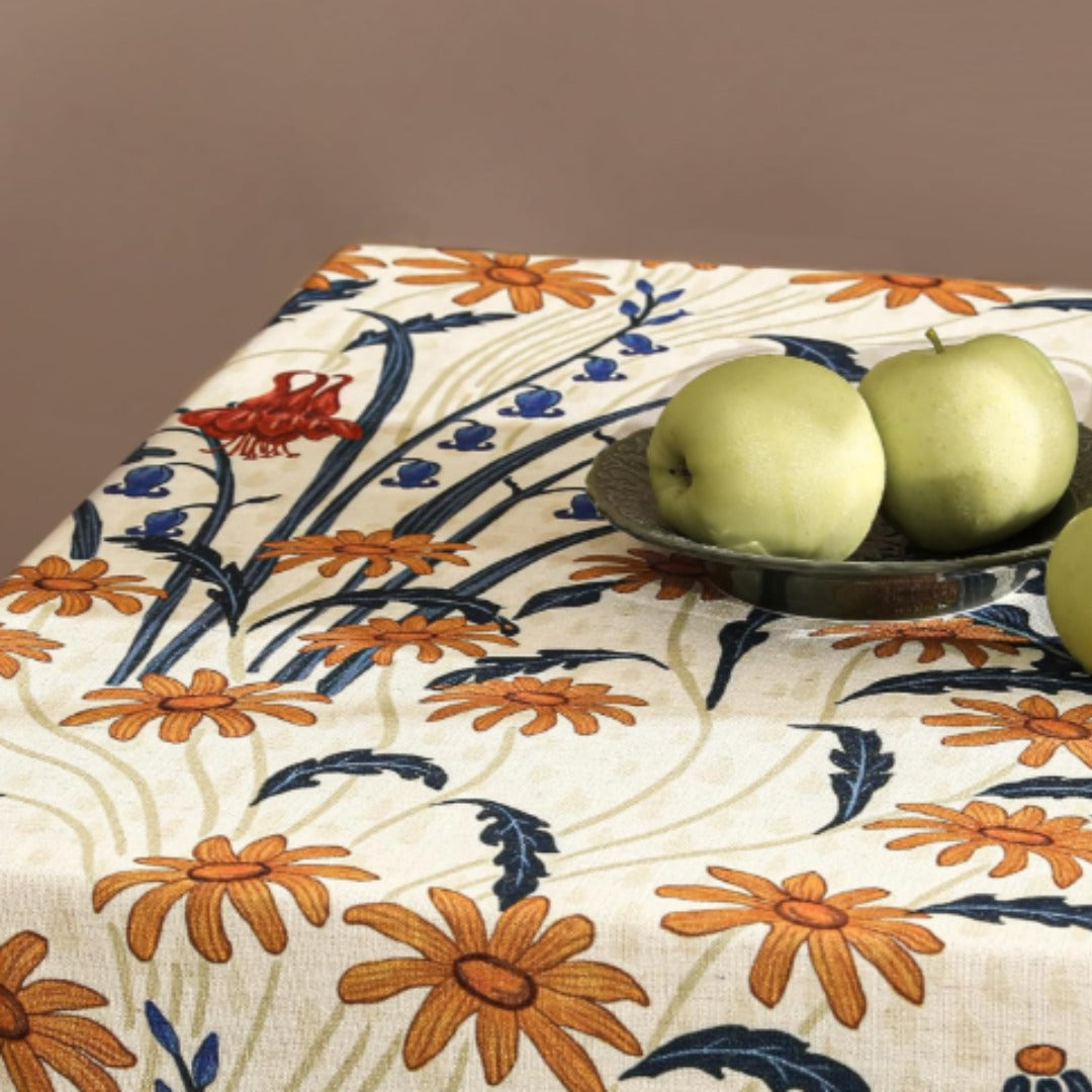 Close-up of orange flowers and navy leaves on a cream tablecloth.