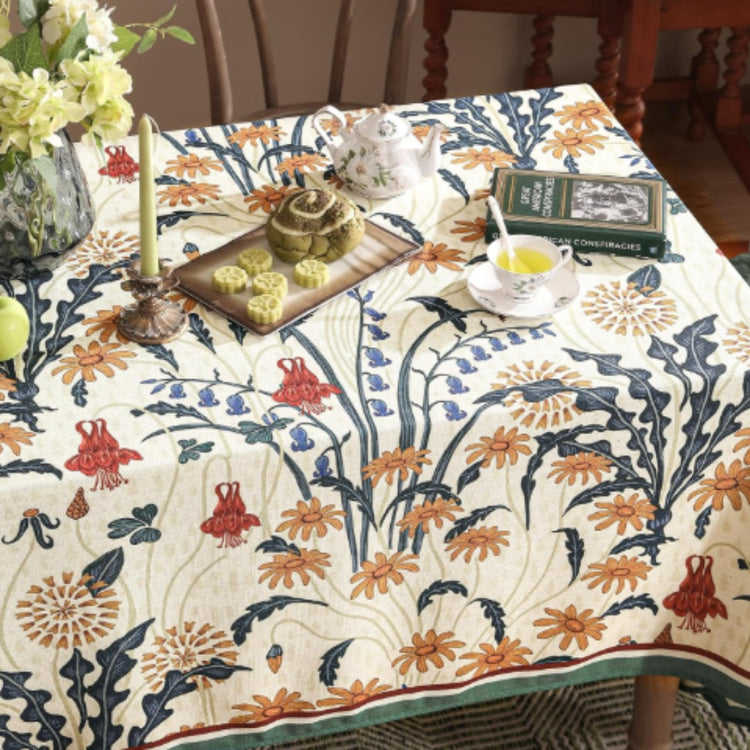 Cream tablecloth with orange and navy botanical motifs and contrasting borders.