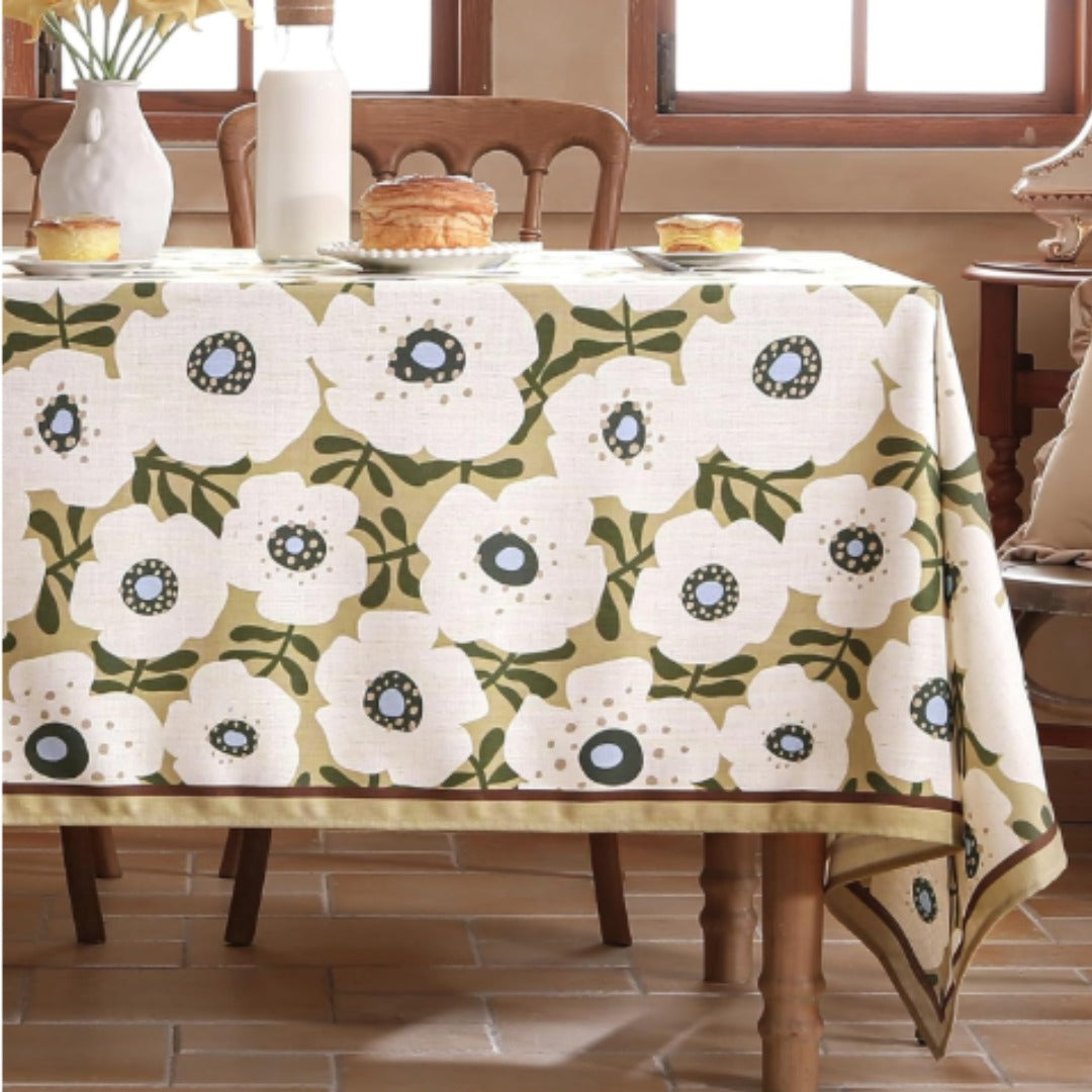 White tablecloth with repeating green ornamental floral medallions.