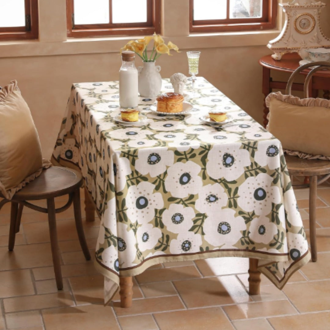 White tablecloth with repeating green ornamental floral medallions.