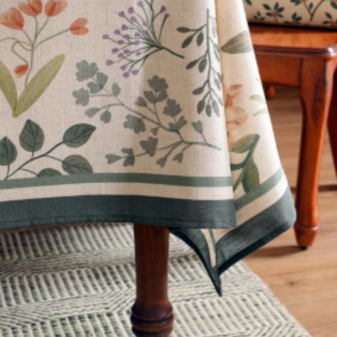 Close-up of floral prints and a dark green border on a cream tablecloth.