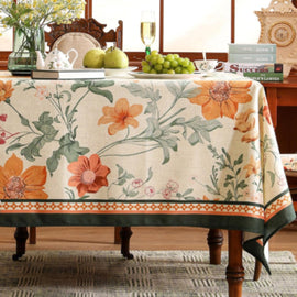 Cream tablecloth with large orange flowers, green leaves and patterned borders.