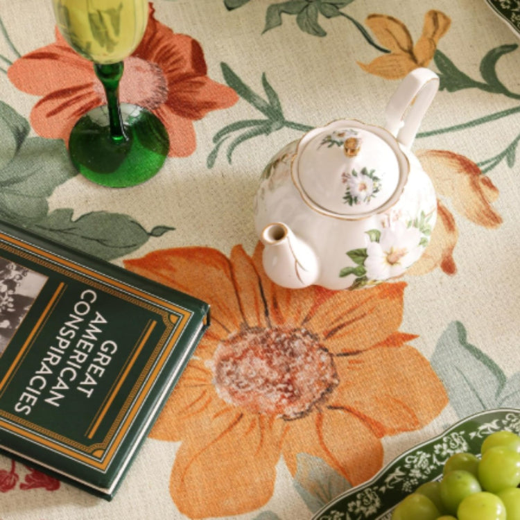 Overhead detail of orange floral motifs on a cream tablecloth.